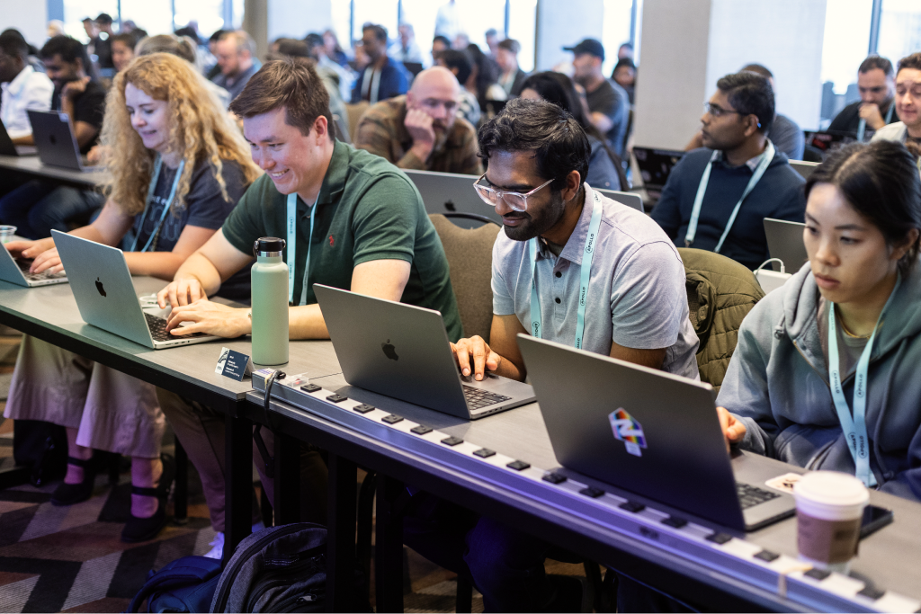 Attendees gathered around laptops in a classroom-style learning session.